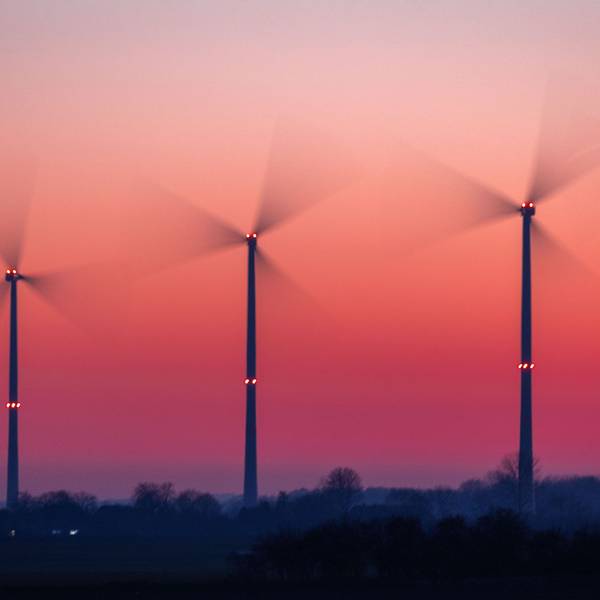 Die Rotoren von Windkraftanlagen drehen sich nach Sonnenuntergang.