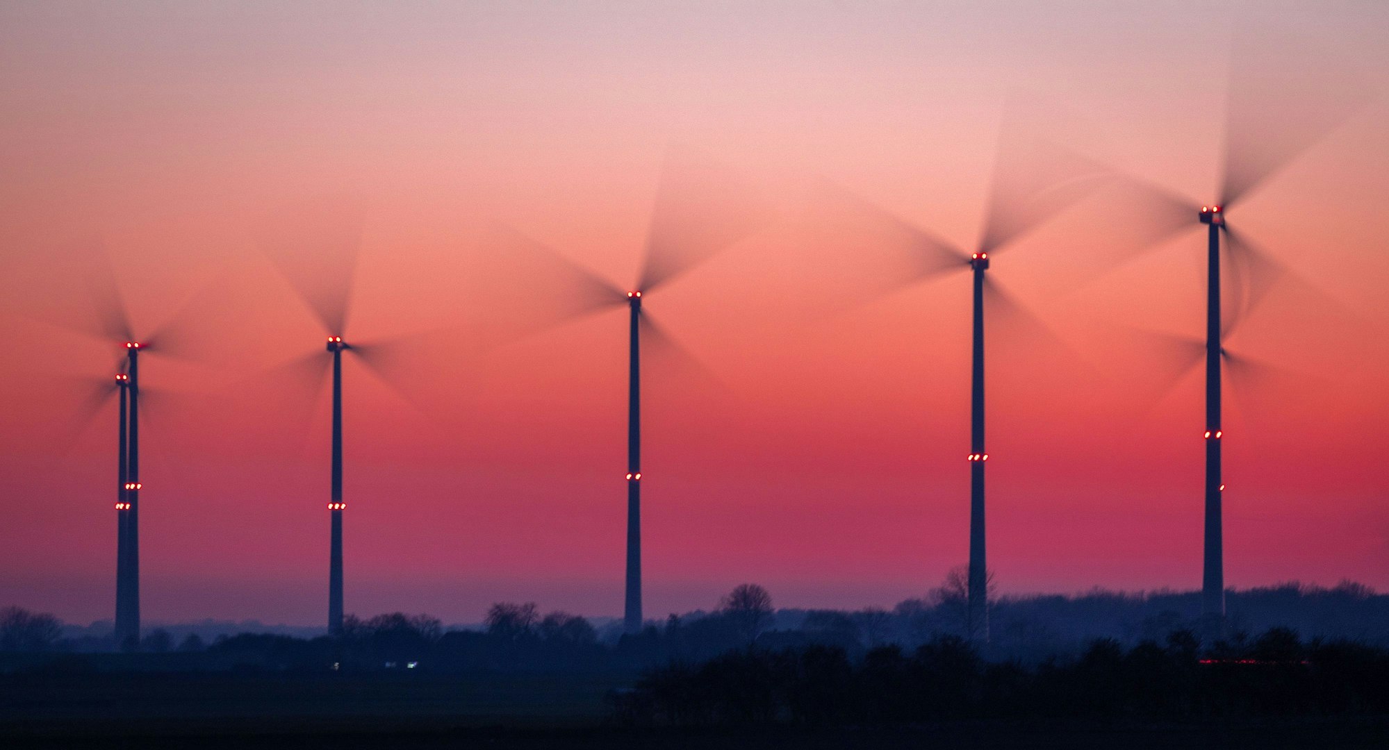 Die Rotoren von Windkraftanlagen drehen sich nach Sonnenuntergang.