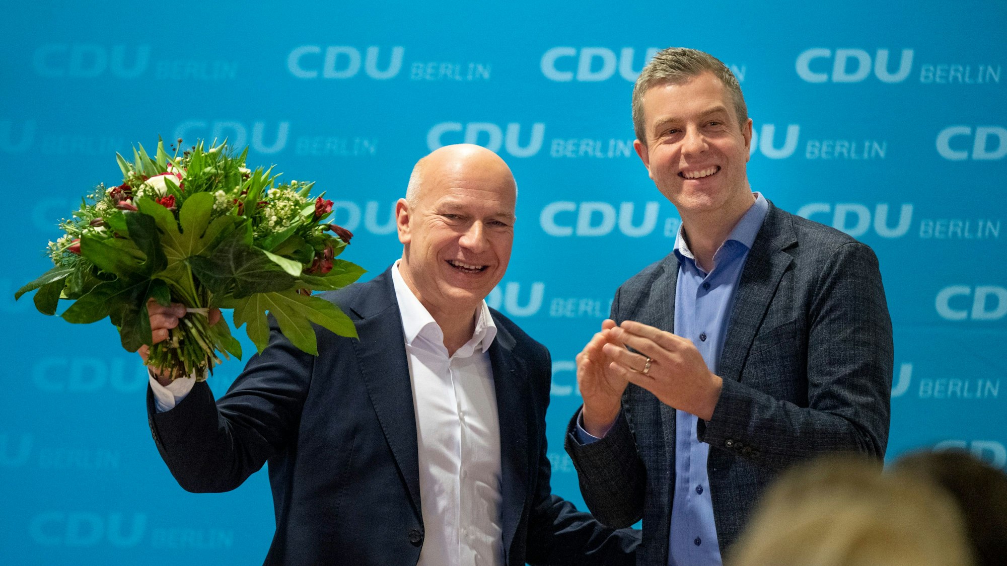 Kai Wegner (l), Landesvorsitzender CDU Berlin hält neben Stefan Evers, CDU-Generalsekretär, lachend einen Blumenstrauß in der Hand.