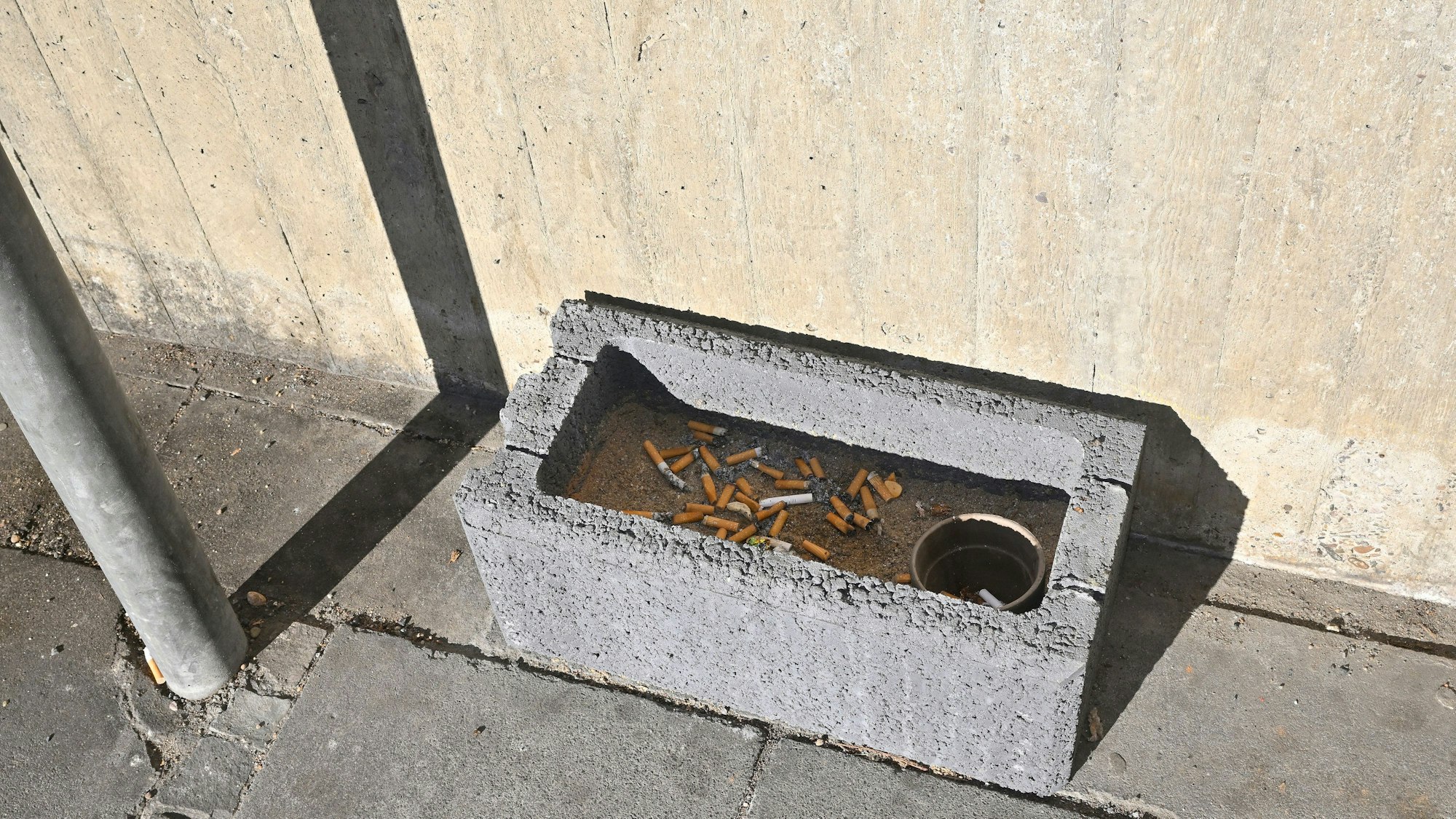 Ein Pflanzstein voll mit Zigarettenkippen.