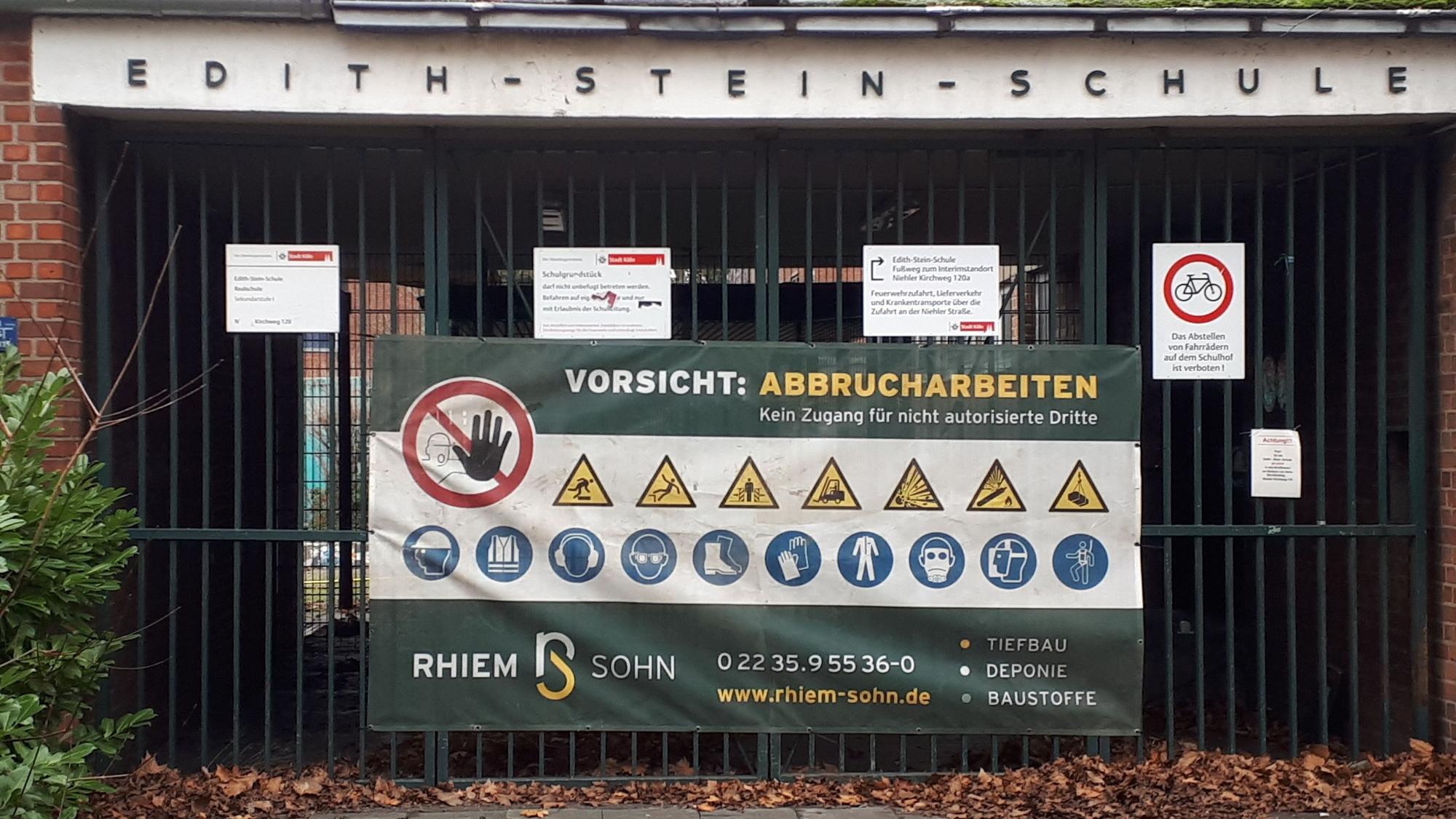 Ein Schild mit „Vorsicht: Abbrucharbeiten“ hängt an dem Tor der Edith-Stein-Realschule am Niehler Kirchweg 120.