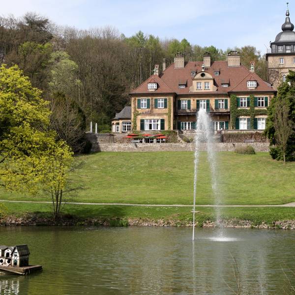 Schloss Lerbach mit Grünanlage und Teich davor.