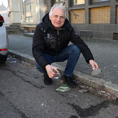 Bernd Trauschies kniet am Straßenrand vor herumliegendem Müll.
