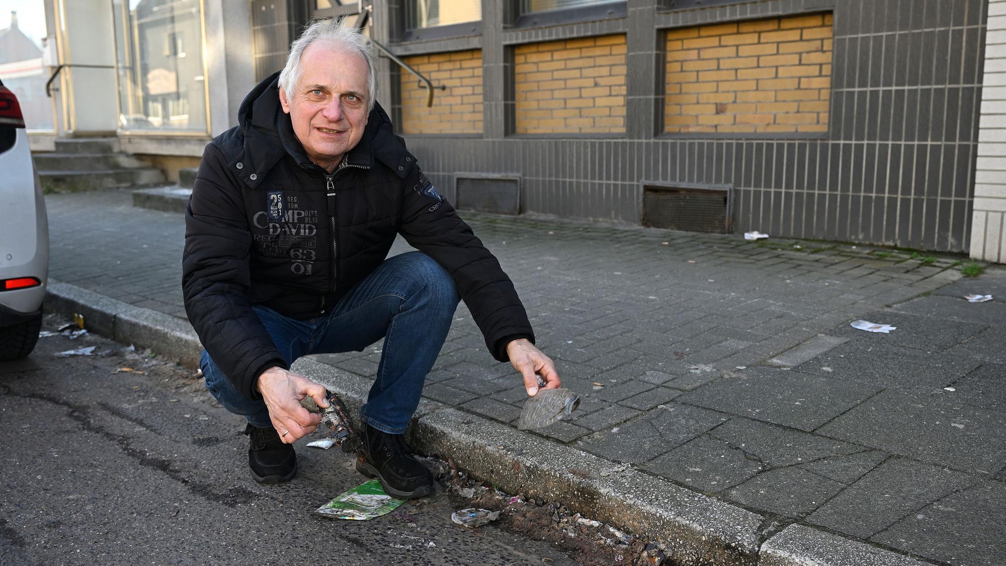 Bernd Trauschies kniet am Straßenrand vor herumliegendem Müll.