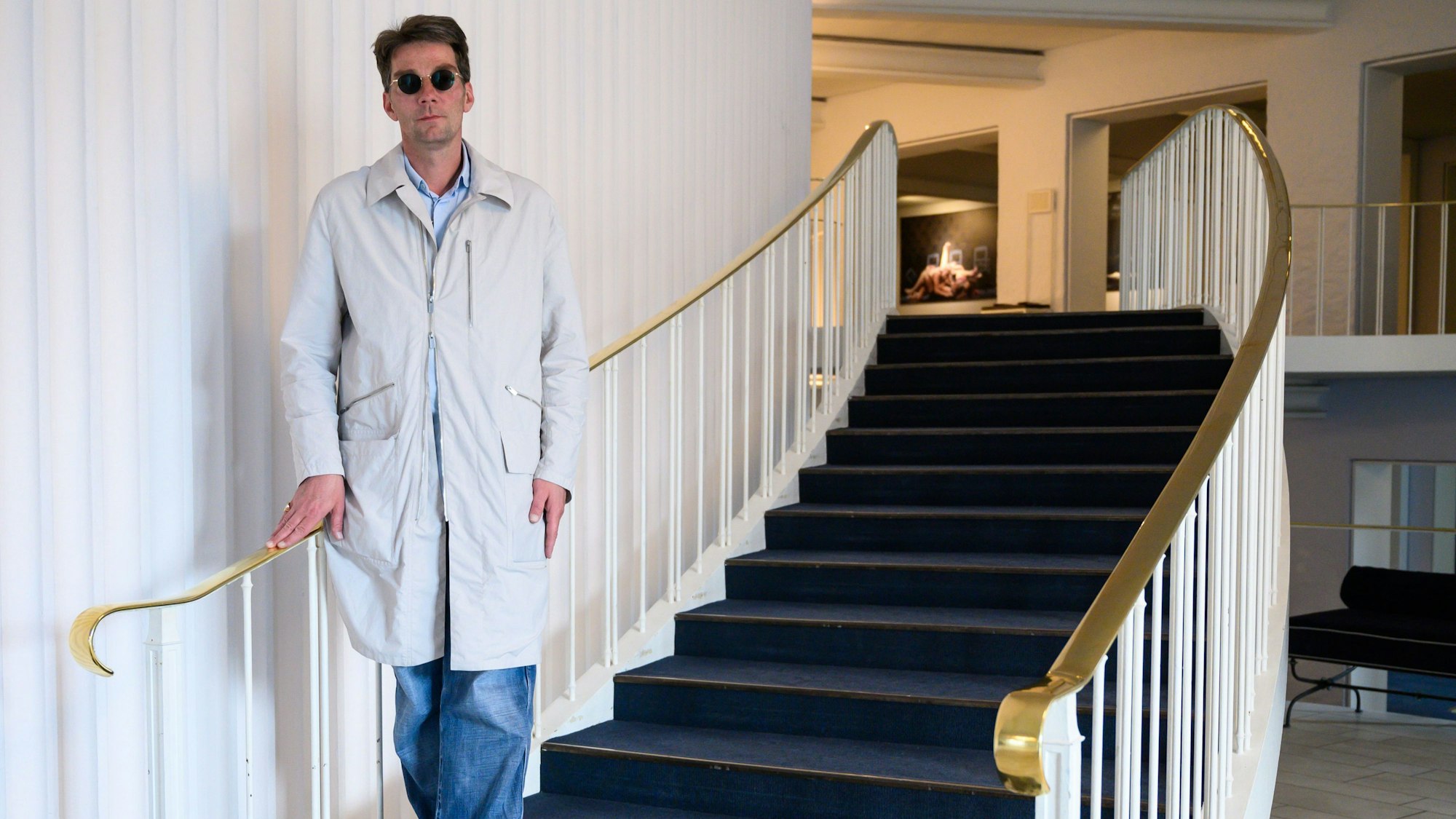Marco Goecke mit Sonnenbrille auf der Treppe im Foyer der Staatsoper.