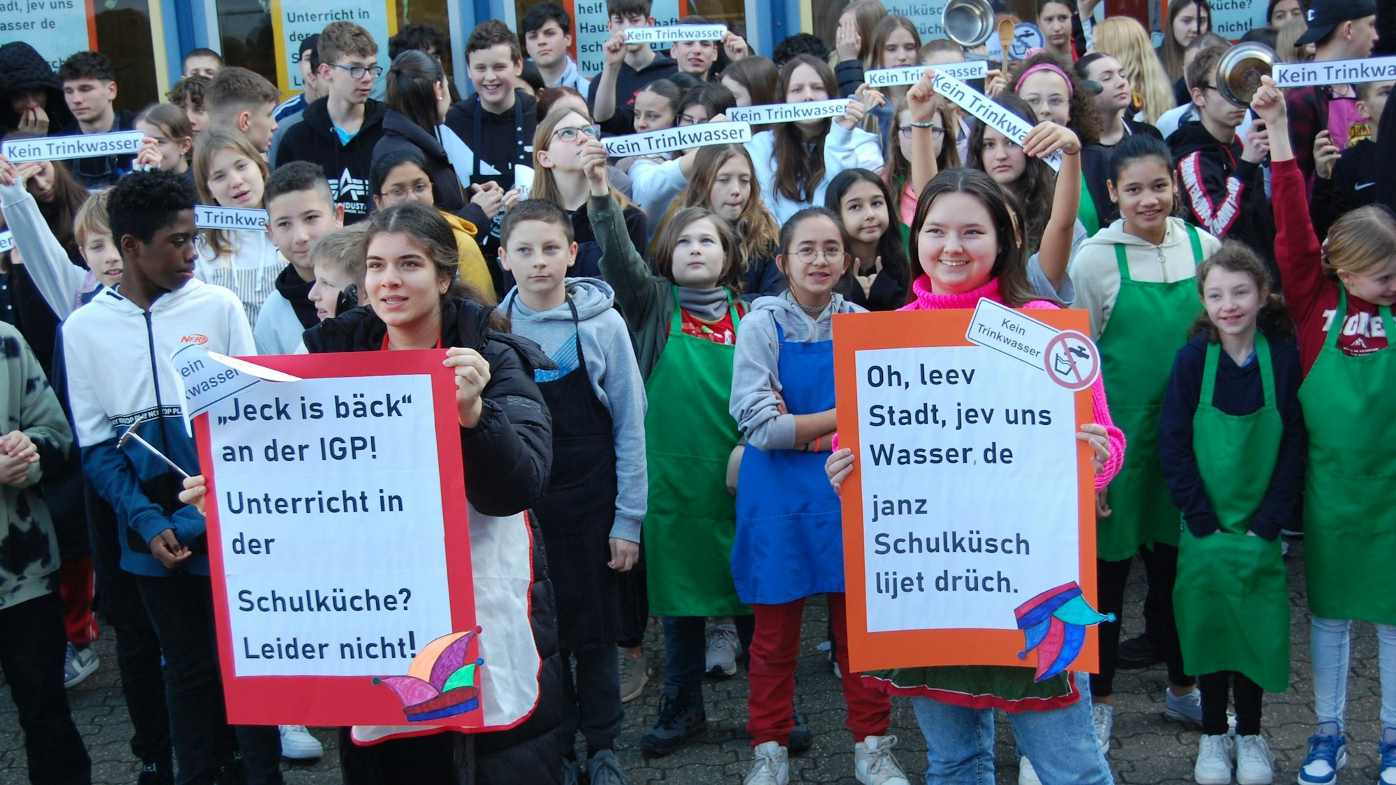 Schüler stehen vor der Schule und halten Protestschilder hoch.