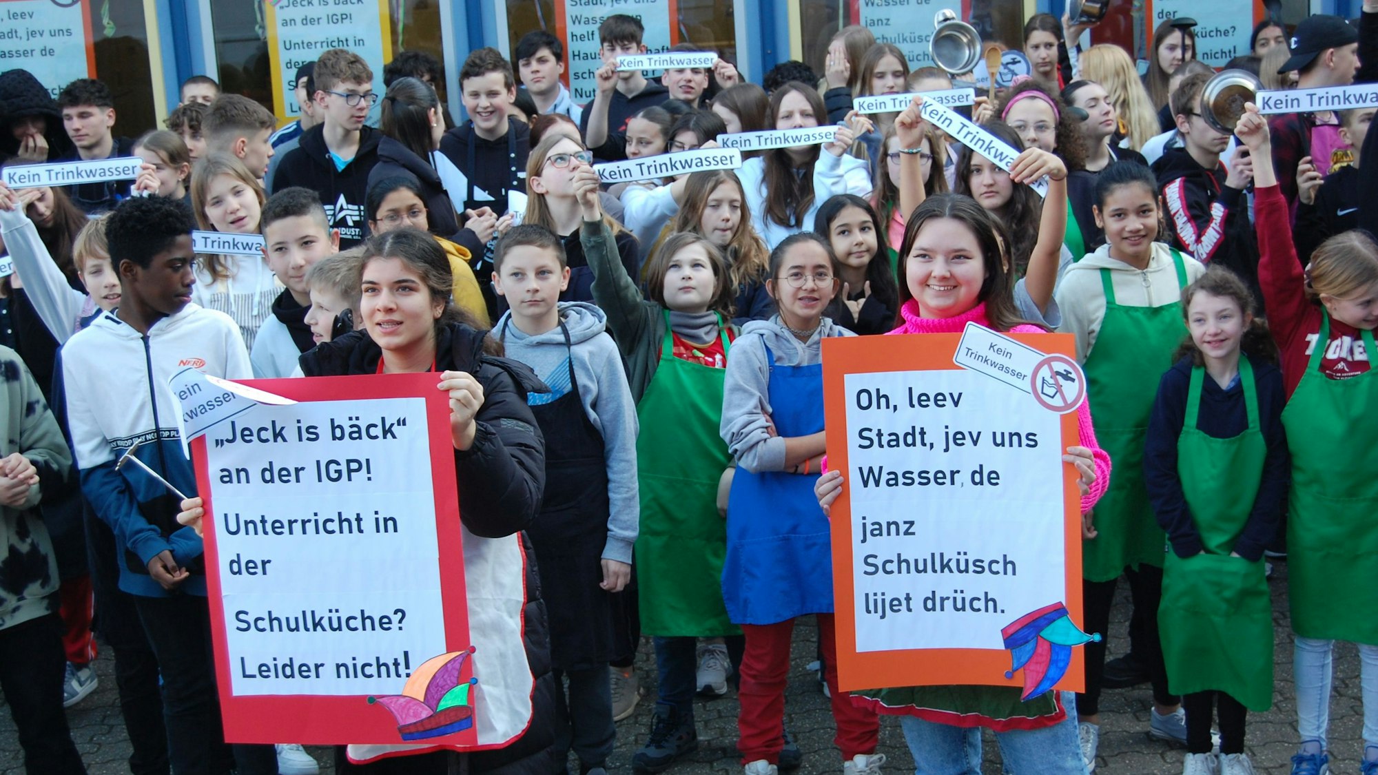 Schüler des Hauswirtschaftsunterrichts der Integrierten Gesamtschule Paffrath (IGP) stehen mit Protestplakaten vor ihrer Schule.