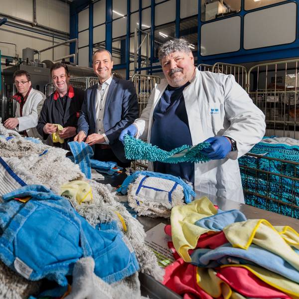 Mehrere Männer stehen hinter einem Berg von bunten Wischbezügen.