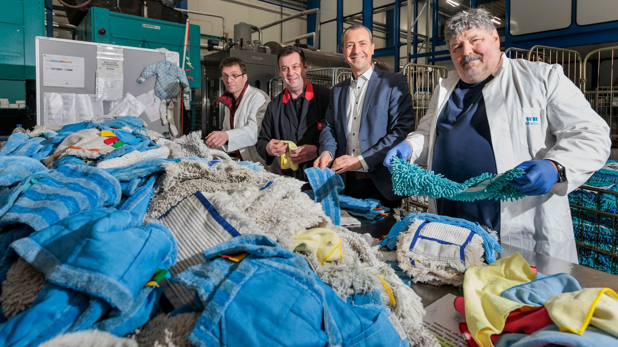Mehrere Männer stehen hinter einem Berg von bunten Wischbezügen.