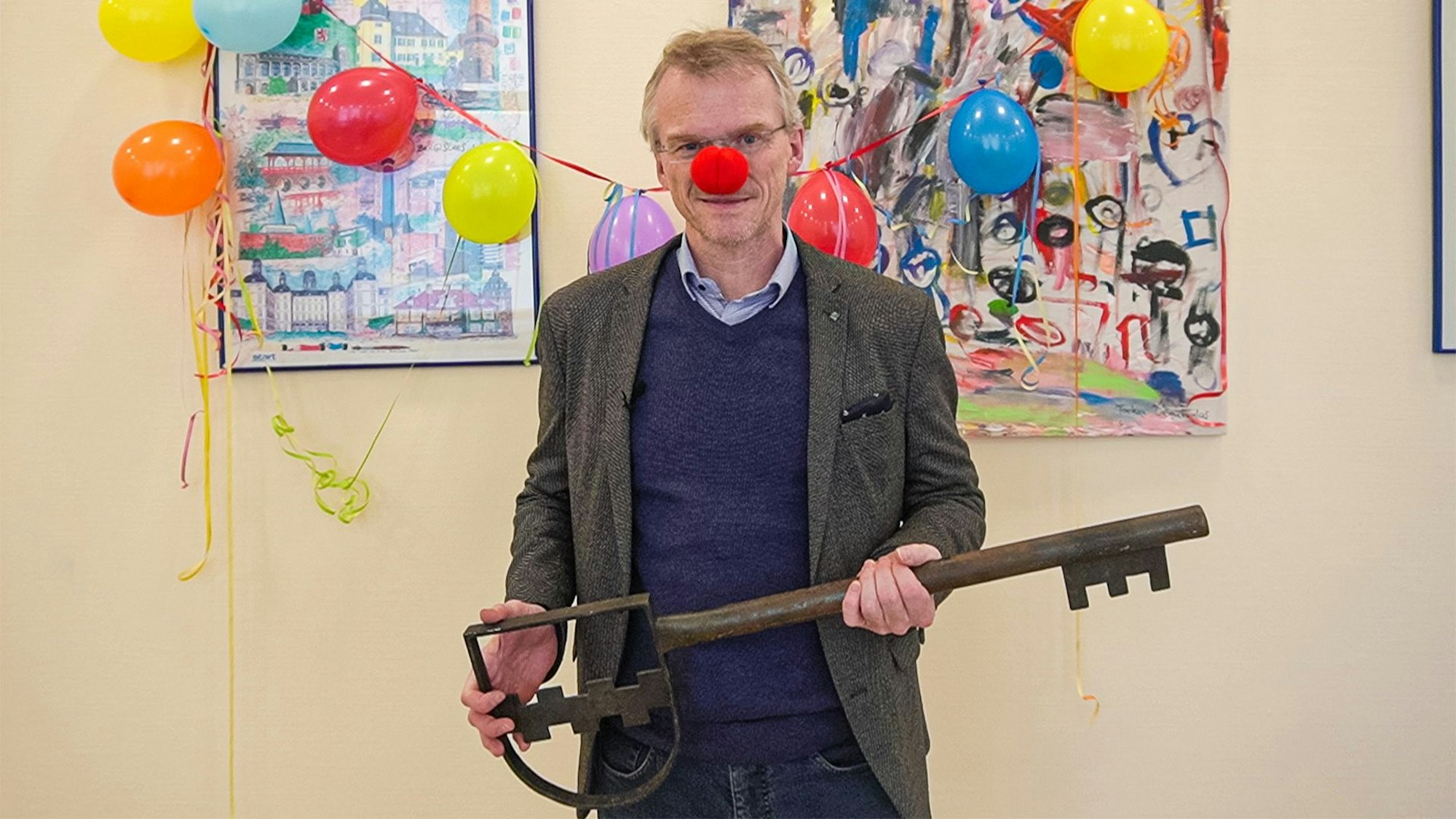 Bürgermeister Frank Stein hat eine Clownsnase an und hält einen großen Rathausschlüssel.