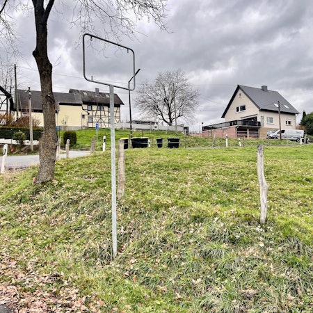 Im Vordergrund die leere Halterung des Schildes, im Hintergrund der Ort selbst.