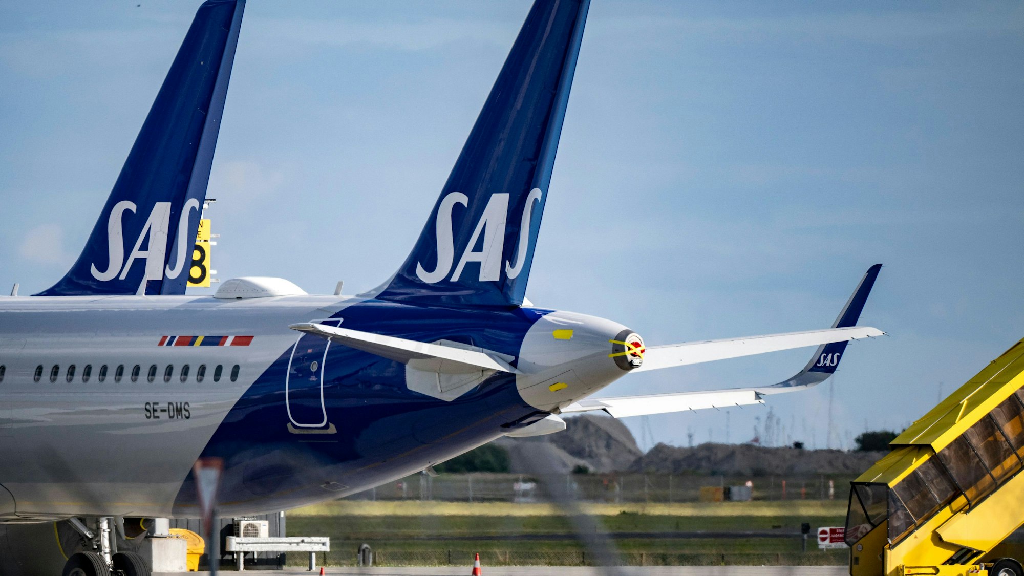 Zwei Airbus A320 der norwegischen Fluggesellschaft SAS stehen neben einer gelben Passagiertreppe. (Symbolbild)