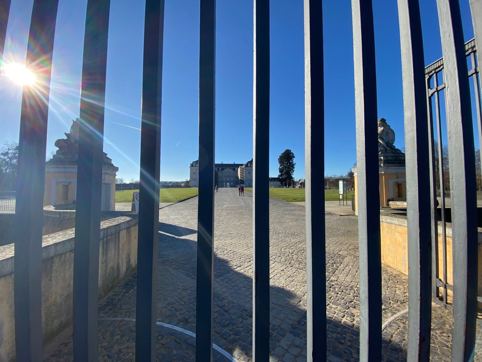 Auf dem Foto ist durch die Streben des verschlossenen Parks der Schlosspark zu sehen.