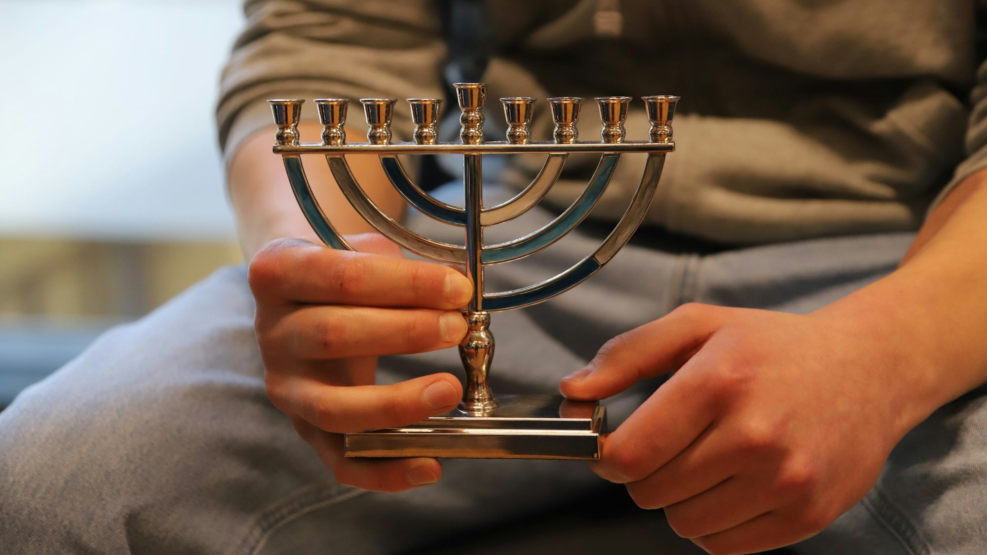 Man sieht eine Person, die einen neunarmigen Leuchter hält.