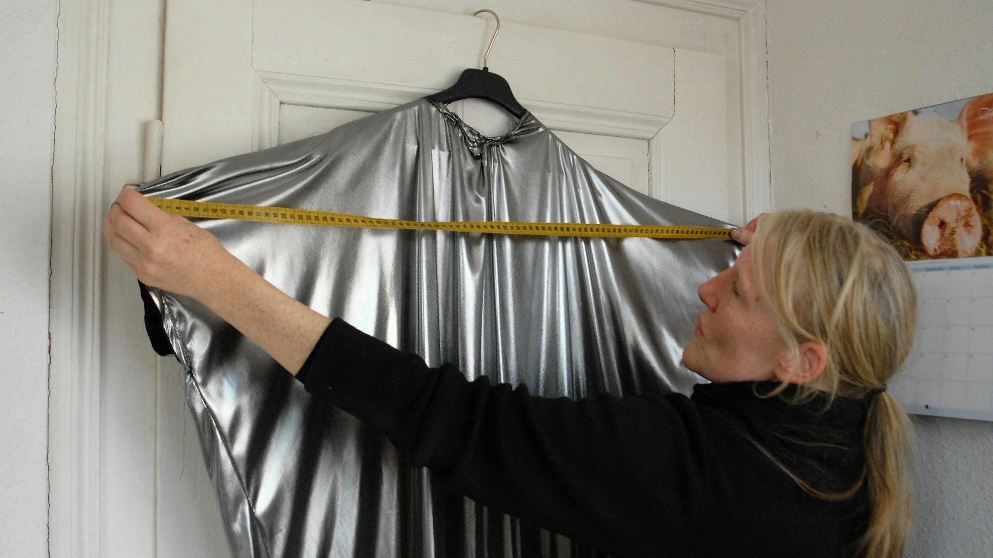 Auf dem Foto ist Ursula Fischer zu sehen, die ein silbernes Kostüm ausmisst.