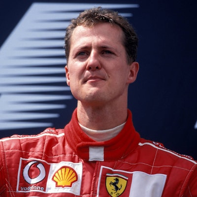 Der ehemalige Formel-1-Pilot Michael Schumacher schaut vor einem Werbebanner in die Ferne.