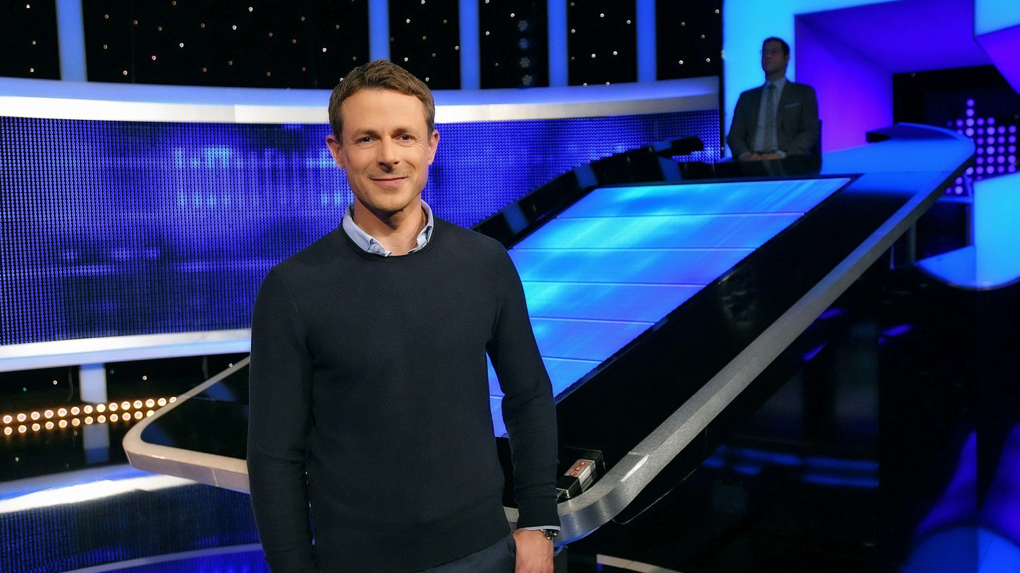 Moderator Alexander Bommes steht in der Studiokulisse von „Gefragt – Gejagt“.