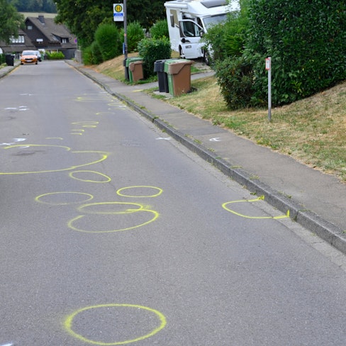 Auf einer Straße sind zahlreiche gelbe Markierungen der Polizei zu sehen.