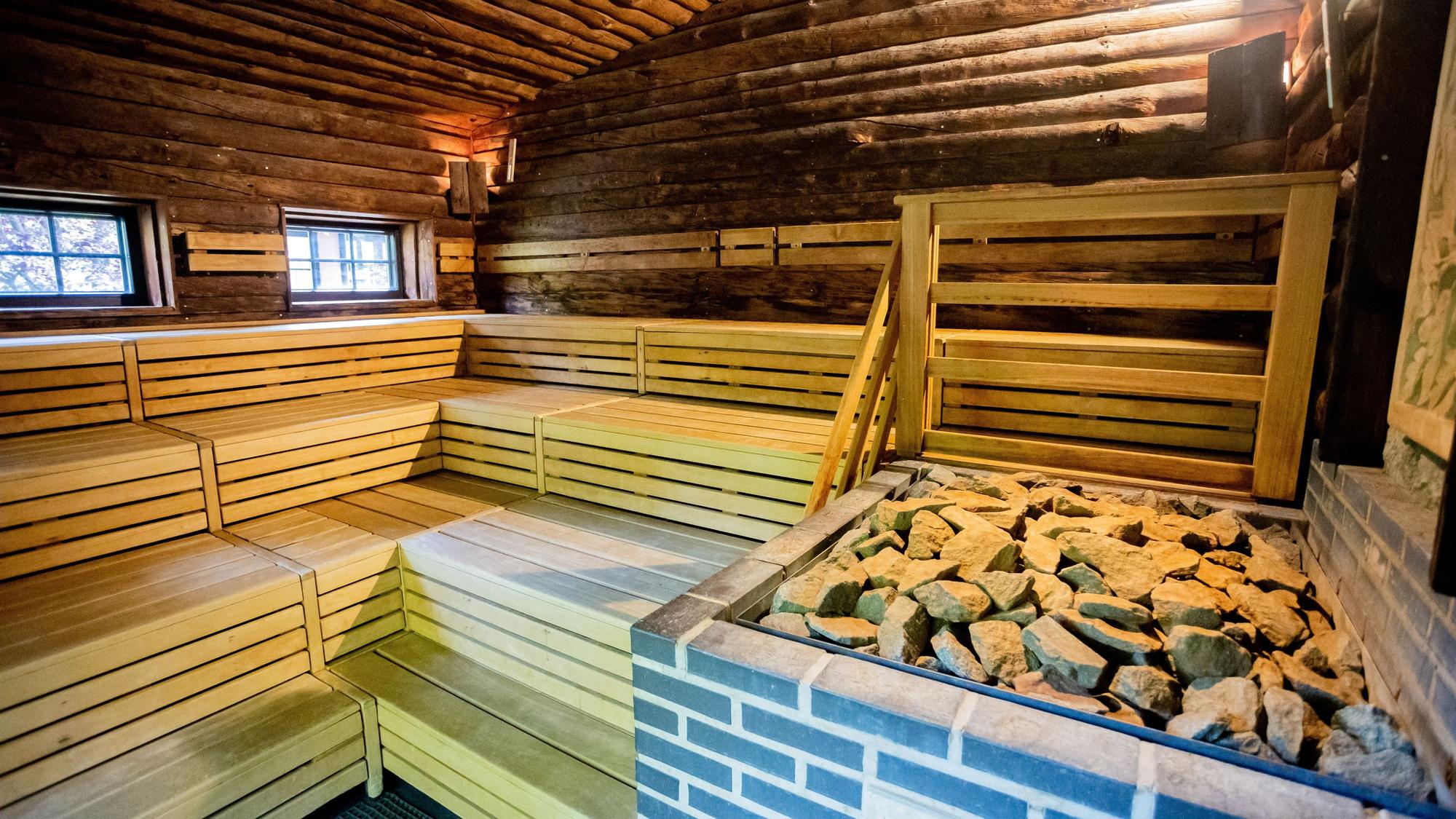 Eine Holzsauna mit mehreren Stufen, Steine liegen auf dem Ofen.