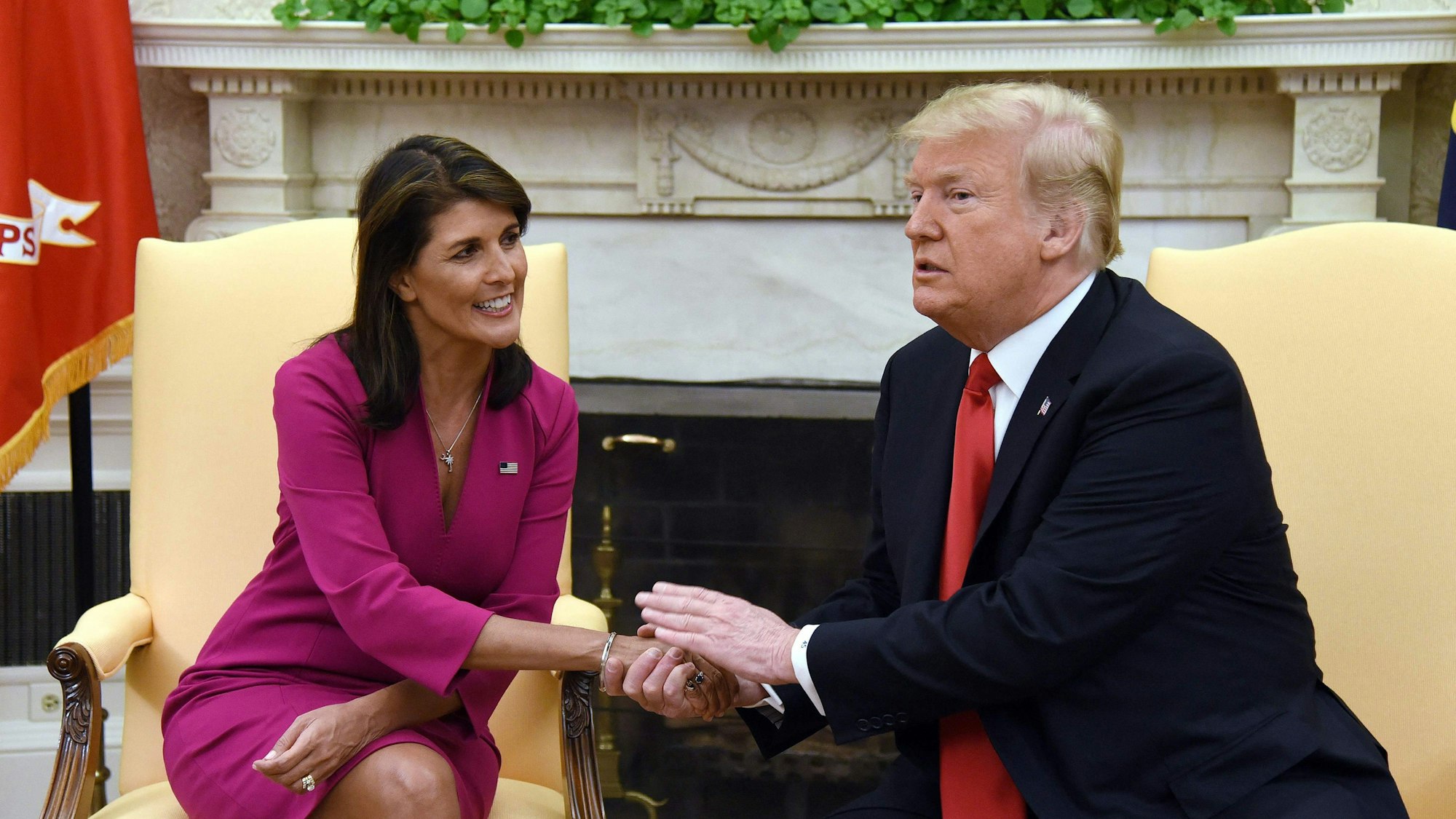 Donald Trump hält Nikki Haleys Hand, während sie ihn anlächelt.