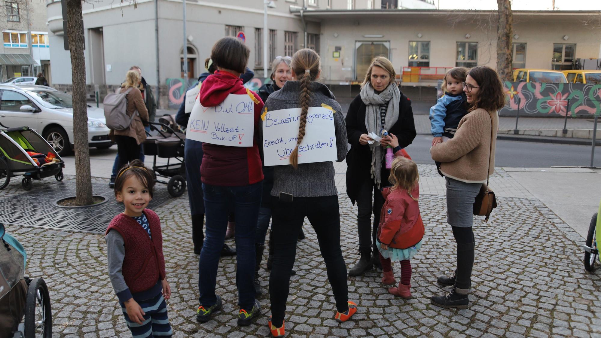 Eltern und Kinder haben sich auf einem Platz versammelt.