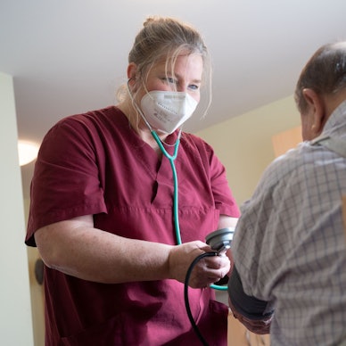 Eine Mitarbeiterin eines Seniorenhaus betreut einen Bewohner.