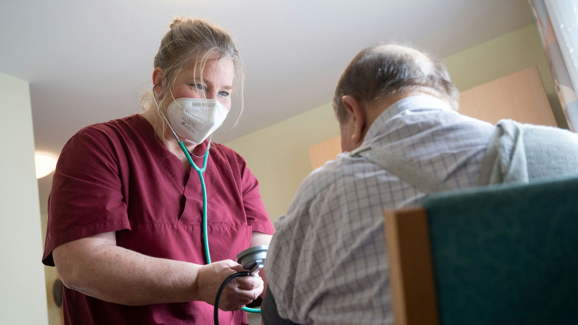 Eine Mitarbeiterin eines Seniorenhaus betreut einen Bewohner.