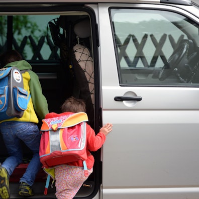 Schulkinder steigen in ein privates Fahrzeug.