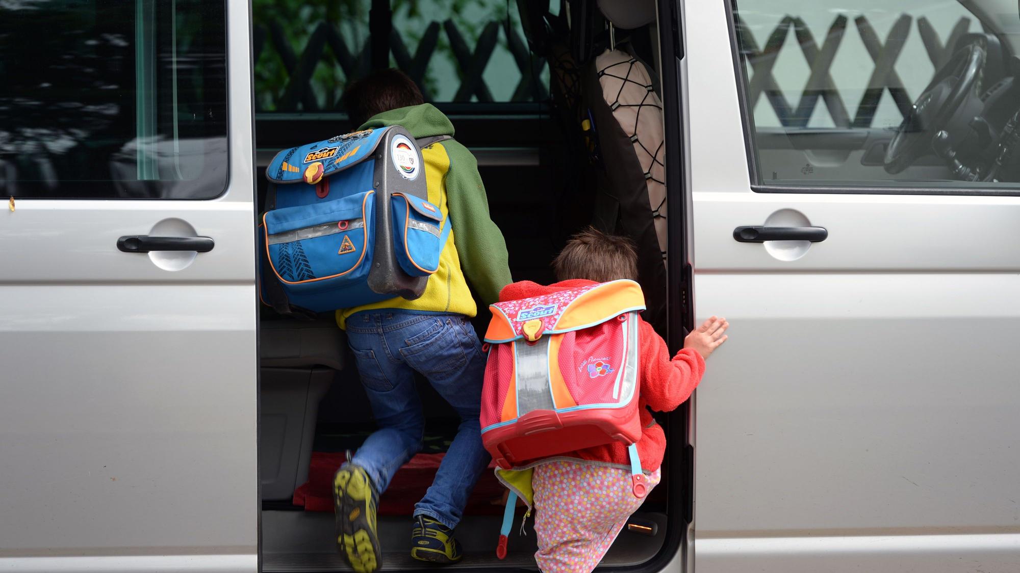Schulkinder steigen in ein privates Fahrzeug.
