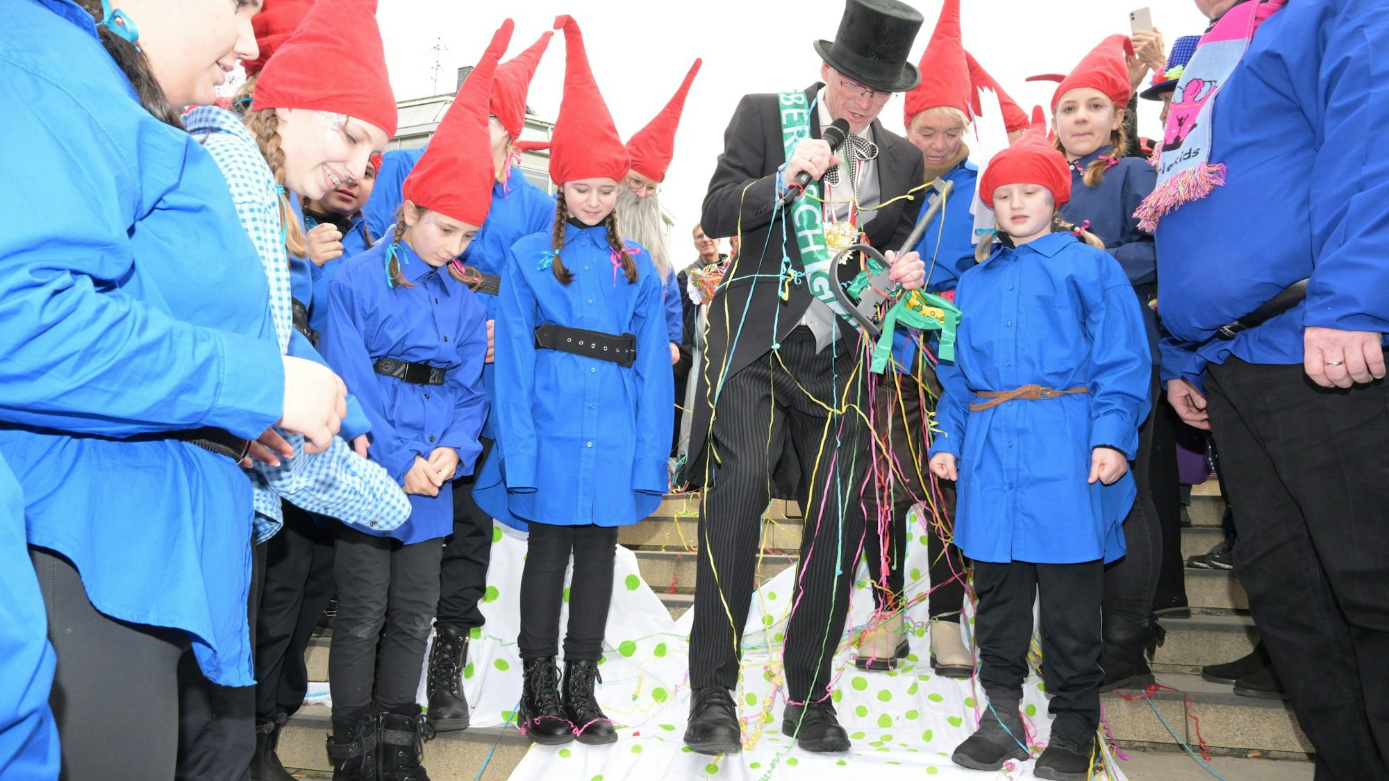Der Bürgermeister steht zwischen den kleinen Heinzelmännchen
