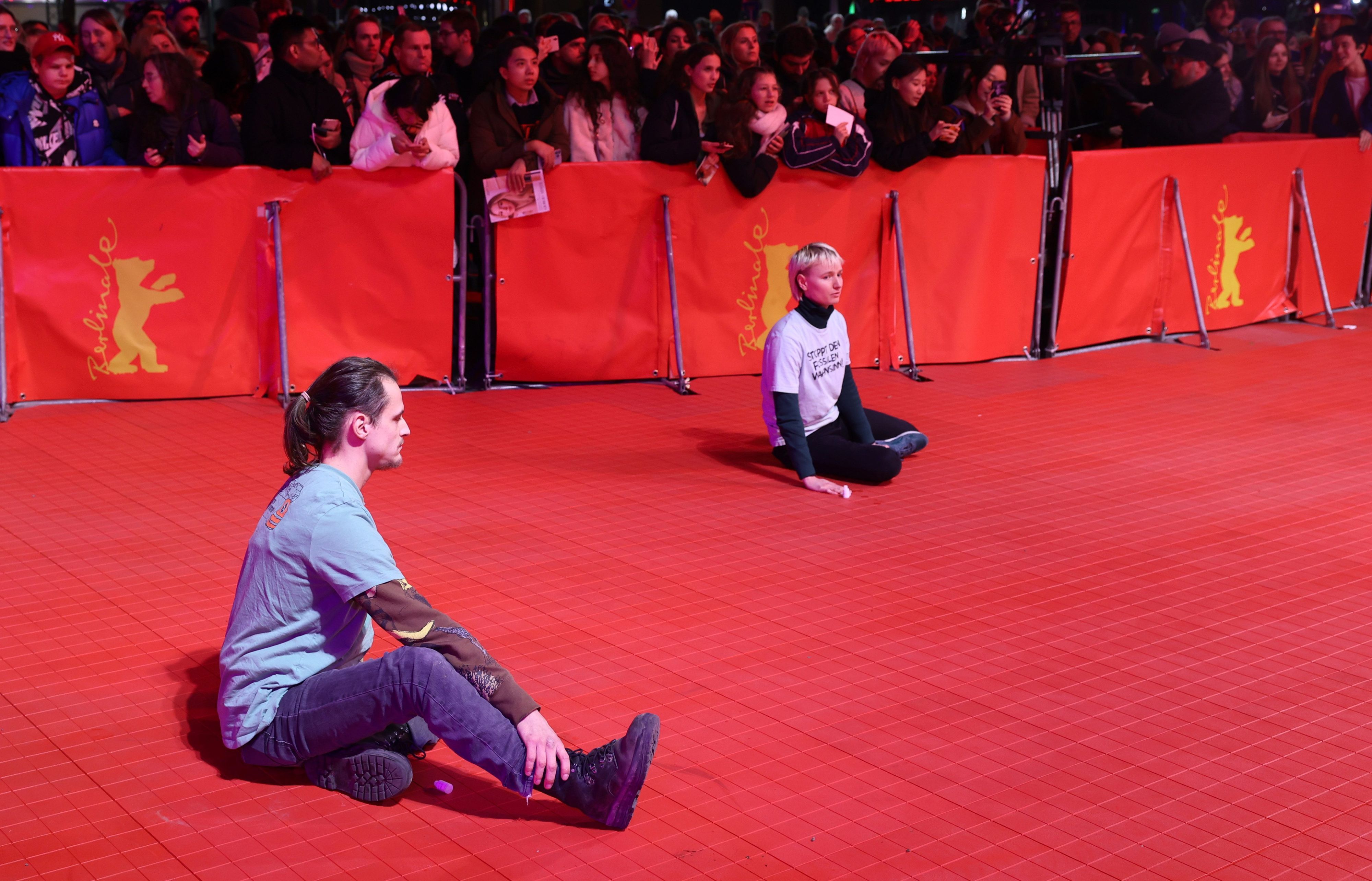 Zwei junge Menschen haben sich auf dem roten Teppich festgeklebt während der Eröffnung der Berlinale.