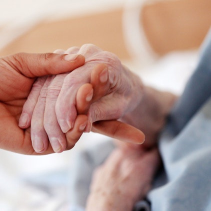 Eine Hand hält die Hand von einer älteren Person.