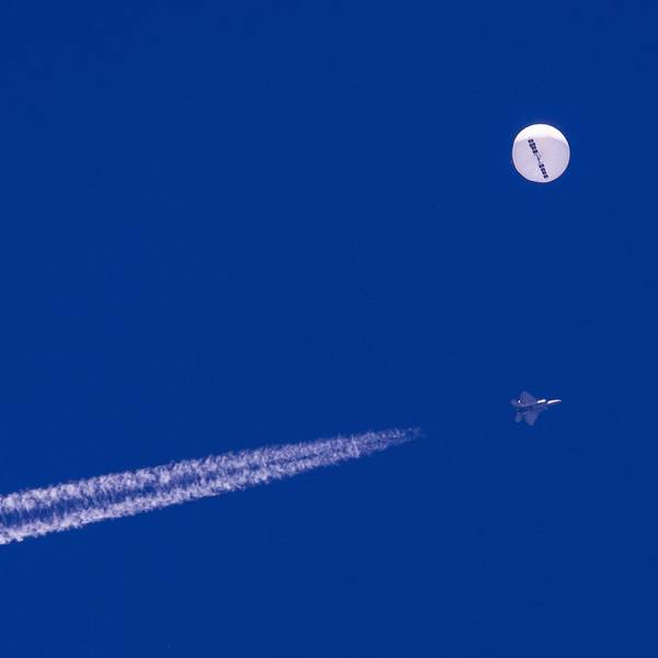 Ein F22-Kampfjet des US-Militärs fliegt in der Nähe des mutmaßlichen chinesischen Spionageballons. Beide sind deutlich am blauen Himmel zu sehen.