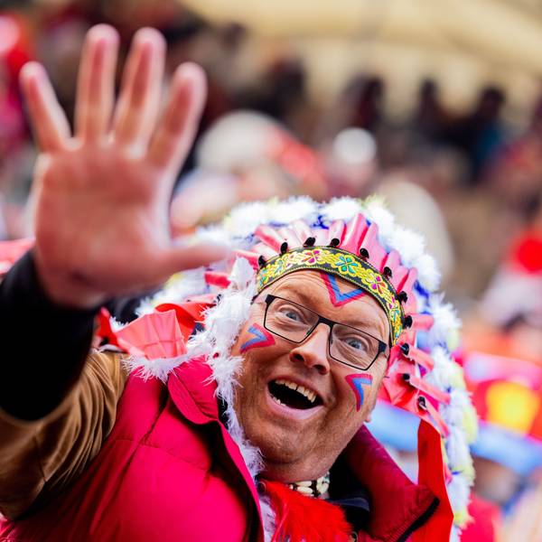 Karnevalisten feiern an Weiberfastnacht die Eröffnung des Straßenkarnevals auf dem Alter Markt. Ein Karnevalist trägt eine bunte Perücke und hält eine Kamera in die Hand.