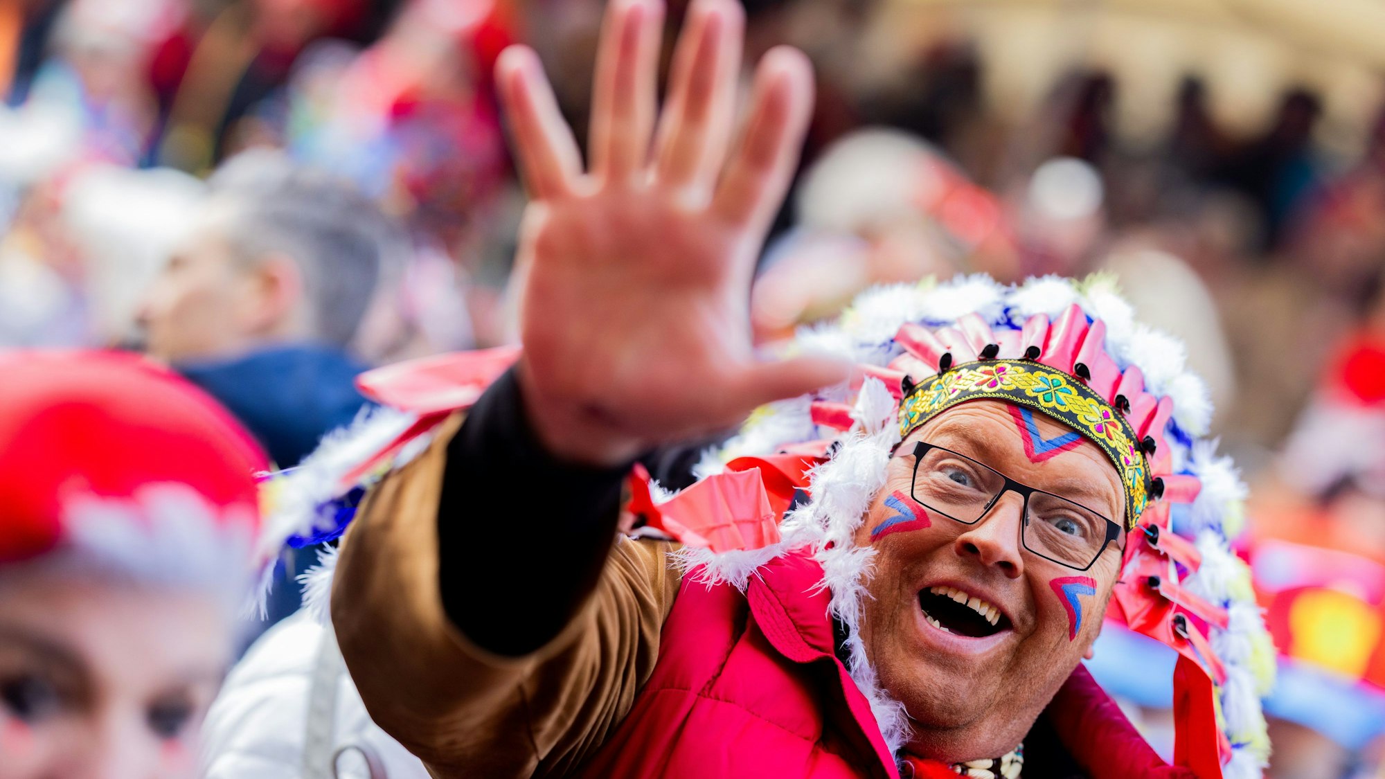 Karnevalisten feiern an Weiberfastnacht die Eröffnung des Straßenkarnevals auf dem Alter Markt. Ein Karnevalist trägt eine bunte Perücke und hält eine Kamera in die Hand.