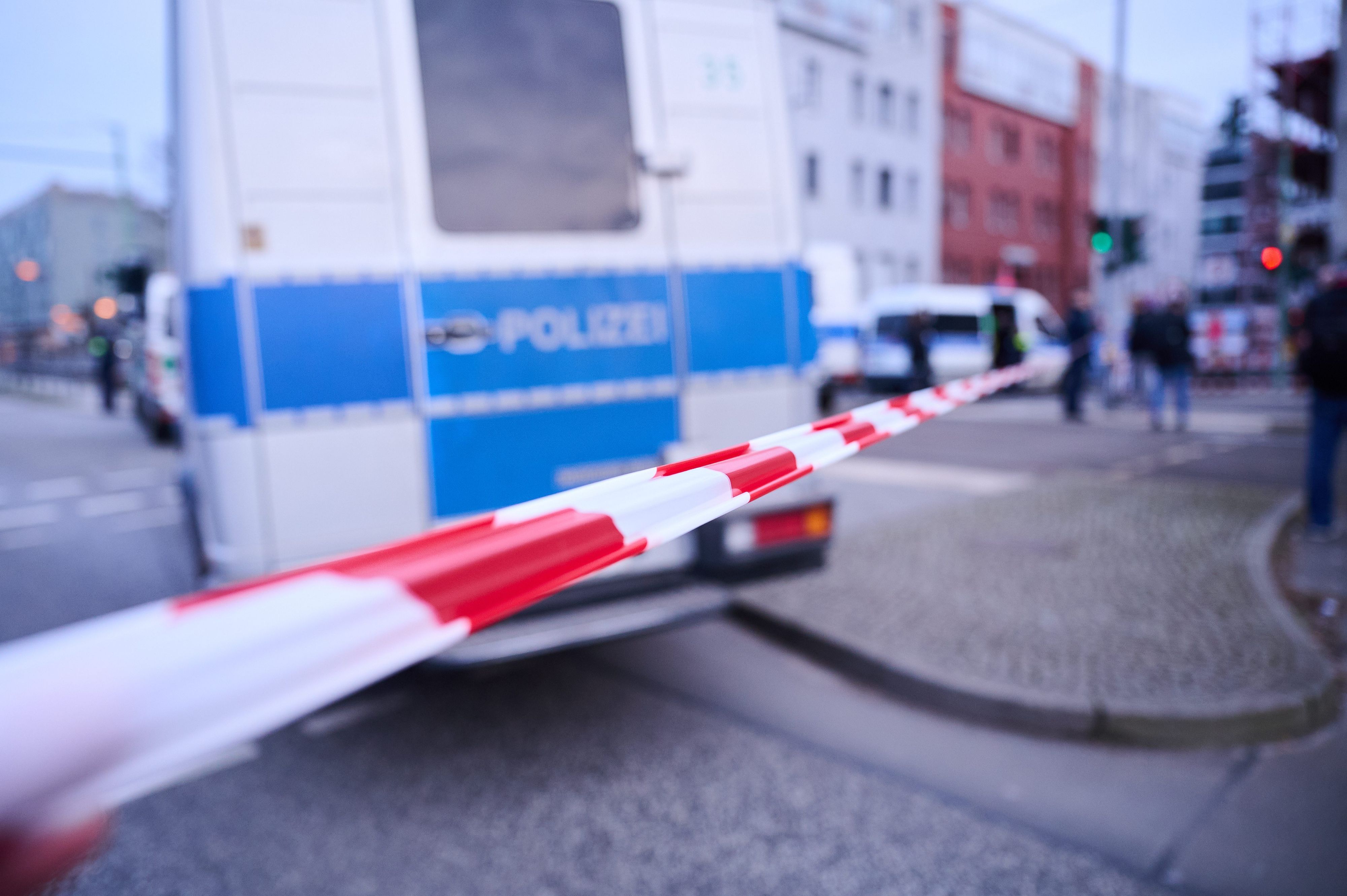 Absperrband vor einem Einsatzfahrzeug der Polizei.