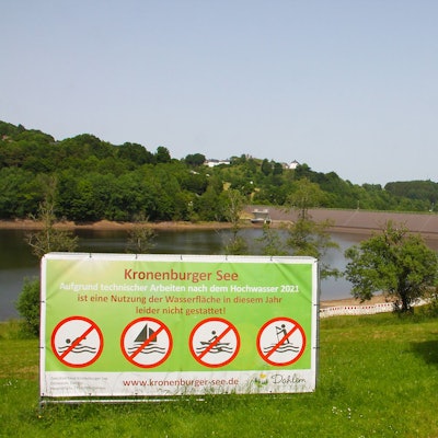 Vor dem Kronenburger See steht ein großes Schild, auf dem steht: „Aufgrund technischer Arbeiten nach dem Hochwasser 2021 ist eine Nutzung der Wasserfläche in diesem Jahr leider nicht gestattet.“