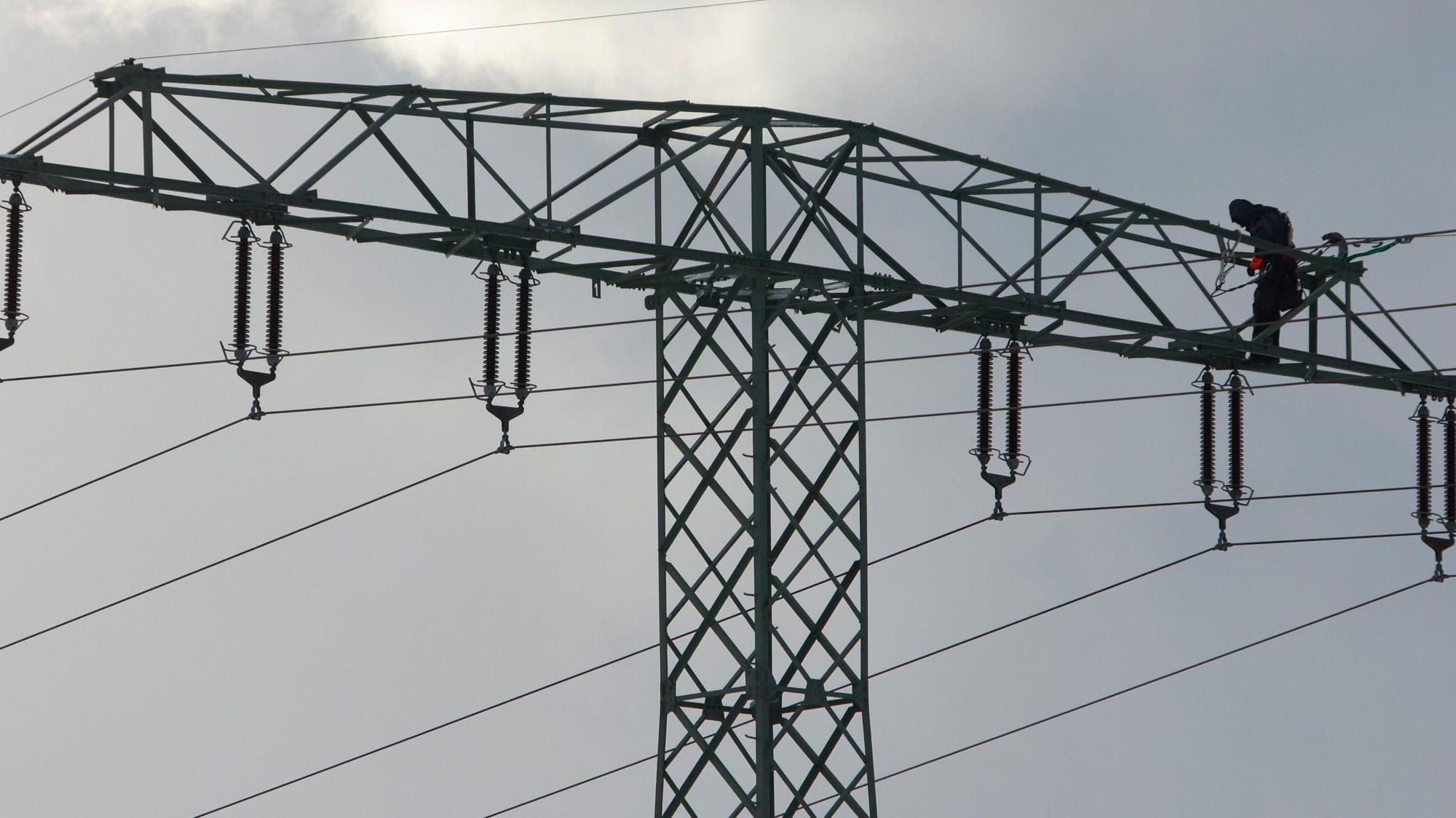 Ein Mann steht auf einem Strommast.