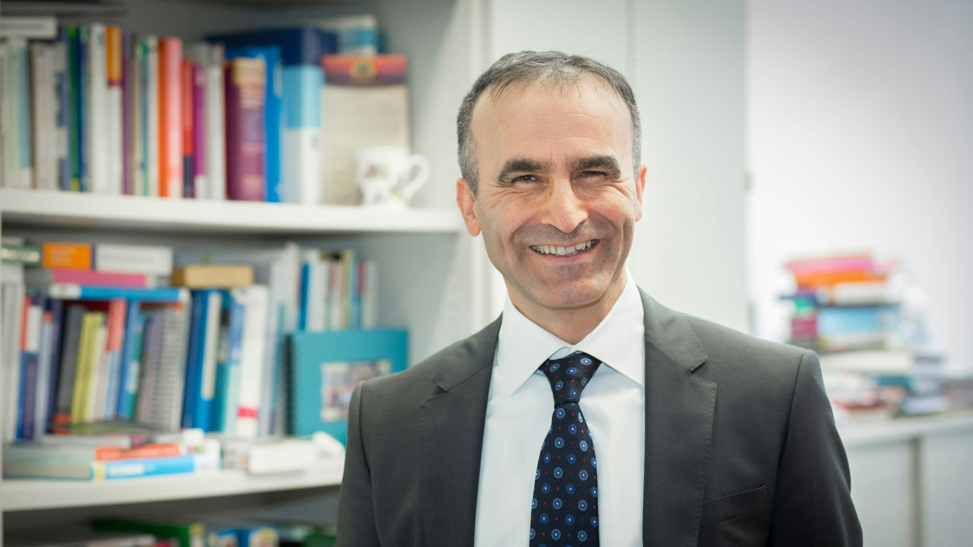 Professor Dr. Sefik Tagay steht vor einem Bücherregal.