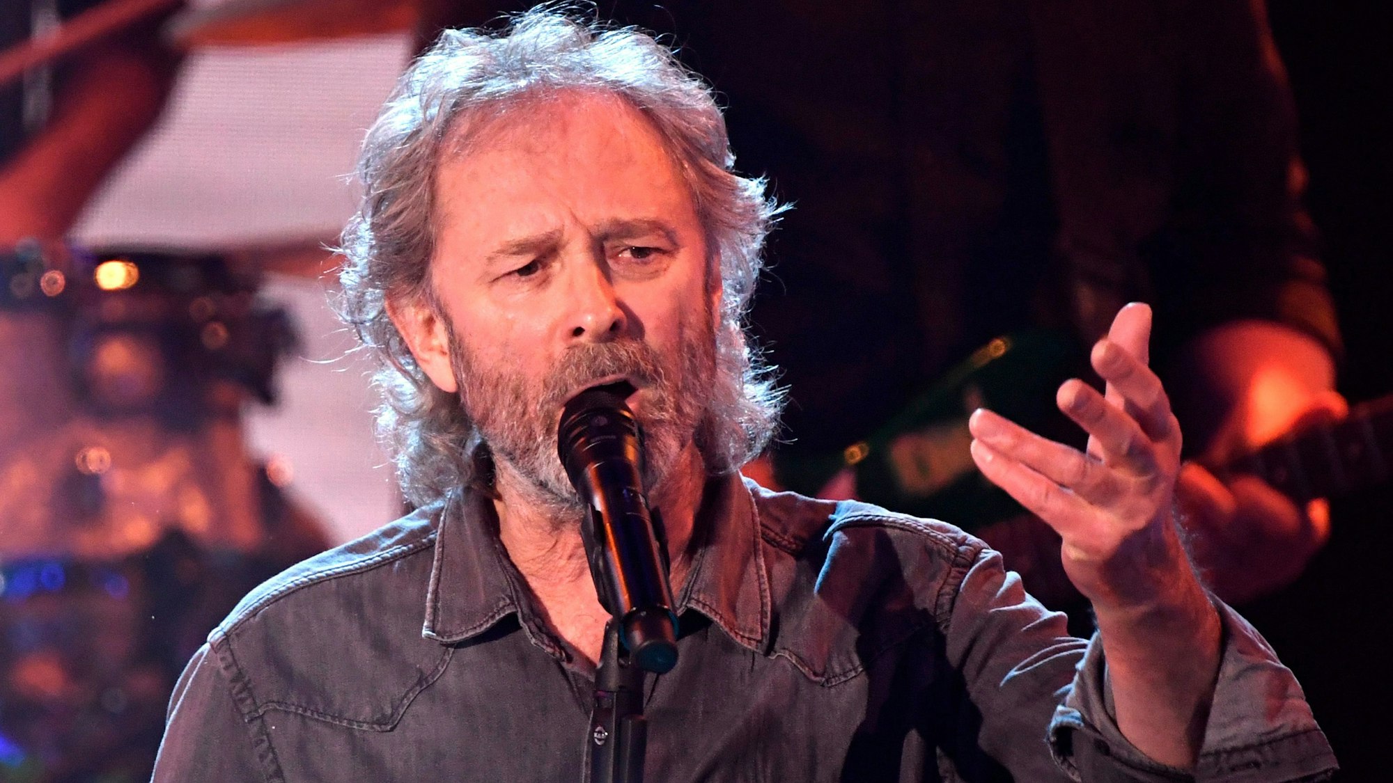 Wolfgang Petry mit grauen langen Haare sinkt in ein Mikrofon.