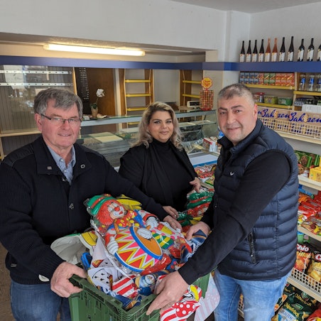 Es sind die Ladenbesitzer mit dem Ortsvorsteher im Kiosk zu sehen.