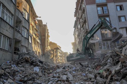 Ein Kran entfernt Schutt von zerstörten Gebäuden im türkischen Hatay