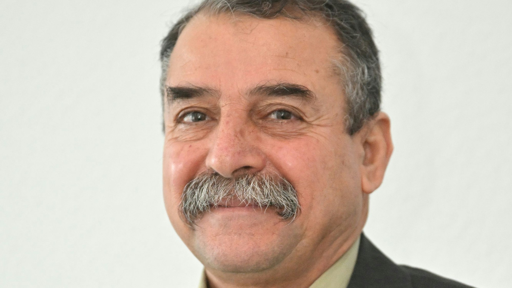 Hamed Abdul steht vor einer weißen Wand.