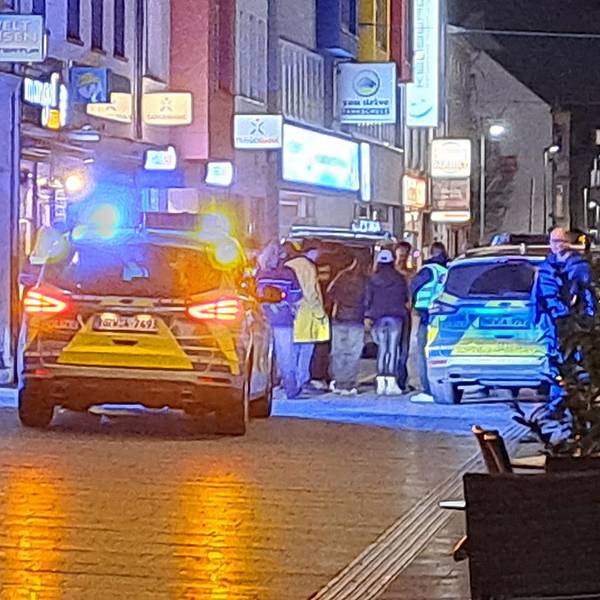 Polizeiautos stehen in einer Einkaufsstraße. Mehrere Personen stehen zwischen den Eisatzautos.