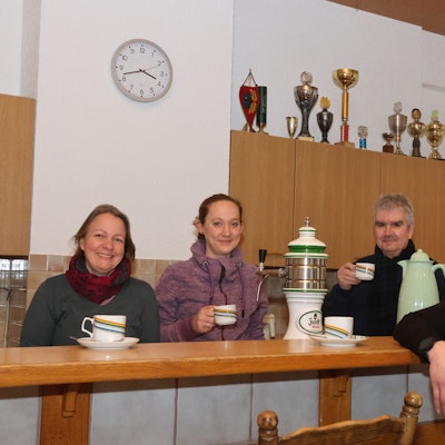Vier Vertreter der Dorfgruppe Kotthausen stehen bei einer Tassee Kaffee zusammen.