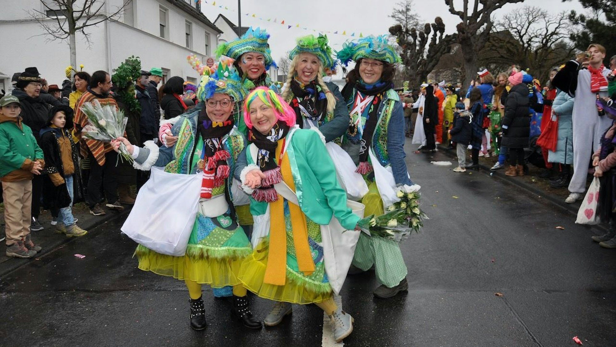 Mehrere Frauen stehen verkleidet auf einer Straße. Um sie herum sind weitere Menschen, die verkleidet sind.