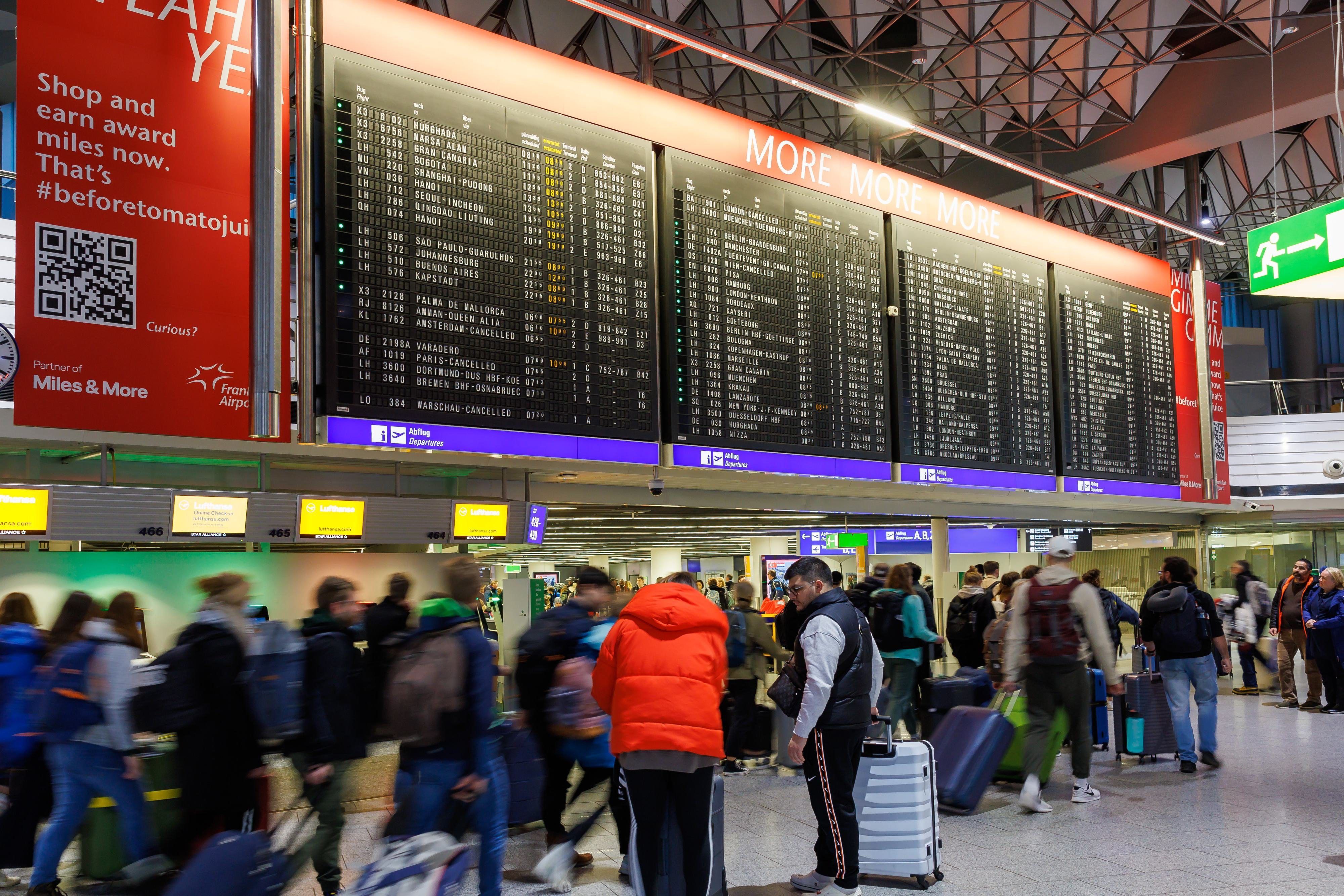 Hessen, Frankfurt/Main: Passagiere stehen vor der Anzeigetafel im Terminal 1.