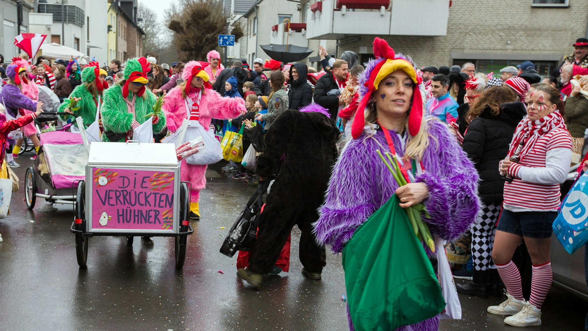 Mehrere Frauen verteilen Kamelle an die Menschen am Straßenrand.
