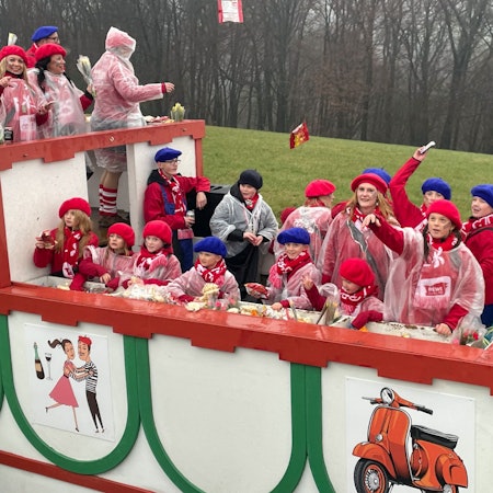 Eine Gruppe jubelt auf einem Karnevalswagen.