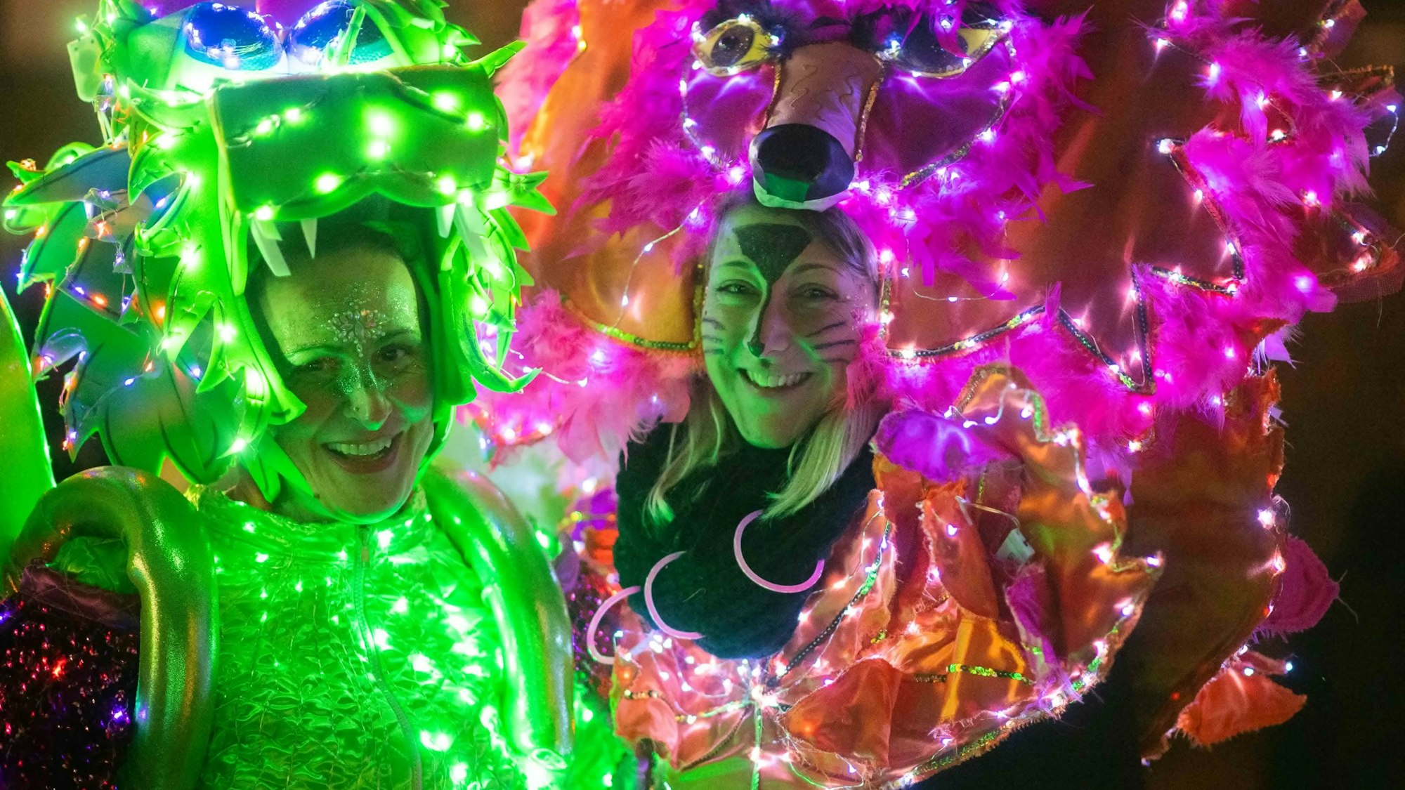Mit unzähligen LED-Lichtern sind die Kostüme der beiden Frauen in Eiserfey verziert: Eine ist als grüner Drache verkleidet, die andere als pinker Panther.